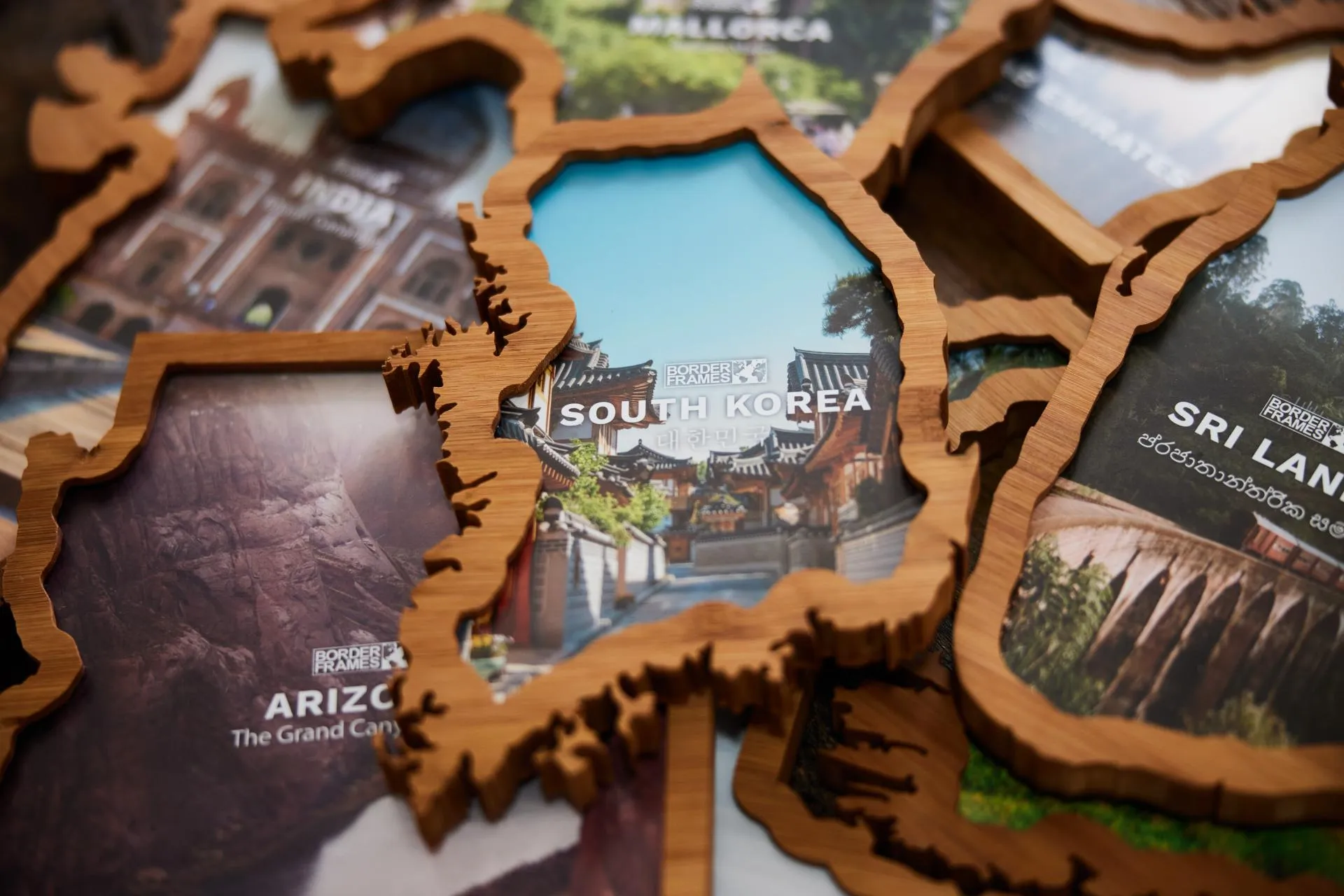 A stack of Borderframes — country‑shaped wooden frames for South Korea, Arizona, Sri Lanka, India and Mallorca