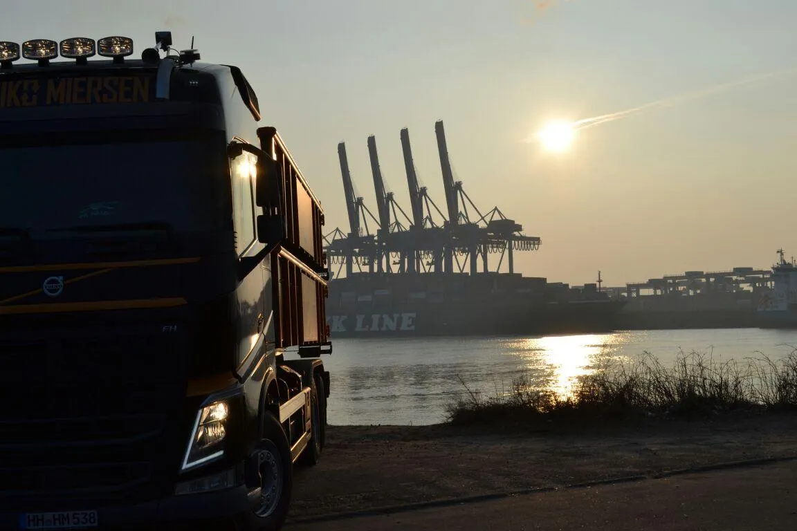 A Miersen truck at Hamburg harbour at sunset, container cranes and a ship in the background